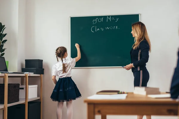 Lição de escola Professor e aluno escrevem em um quadro-negro — Fotografia de Stock