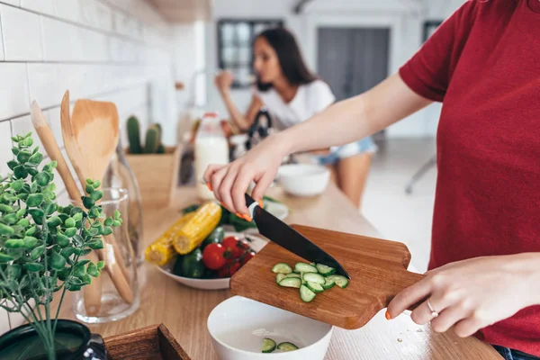 Female hand with knife cutting cucumbers on board. — Stock Photo, Image