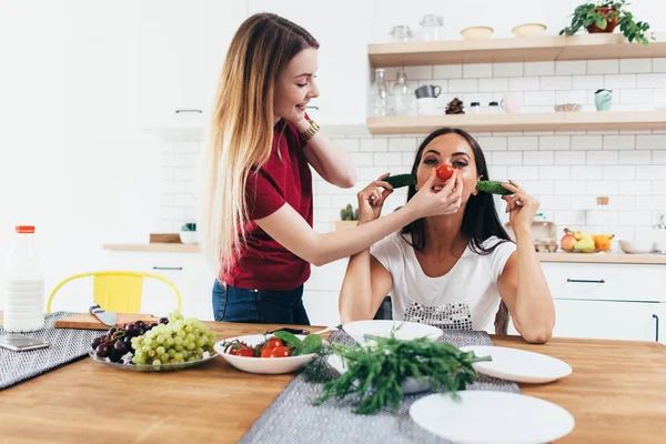 Girls fooling around in the kitchen playing with vegetables. — Stock Photo, Image