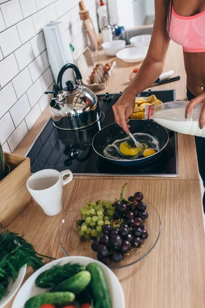 Mujer fitness preparar omlette en la cocina. Mezclar leche y huevos en una sartén . — Foto de Stock