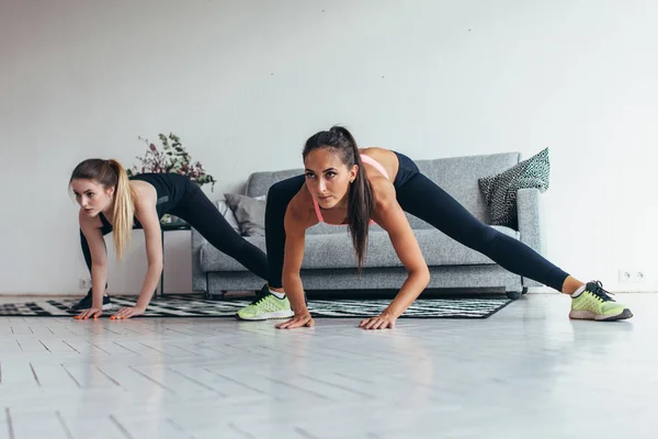 Två passar flickor gör träning utför laterala utfall hemma. — Stockfoto