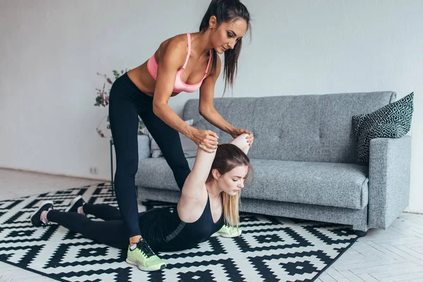 Fit vrouw hielp vriend in achter het uitrekken zich training thuis — Stockfoto