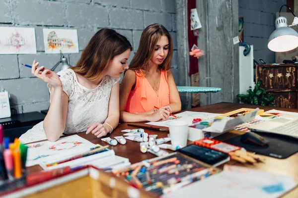 Дизайнери робочого простору. Дві жінки-художниці малюють декоративні елементи, що сидять за столом у творчій студії — стокове фото