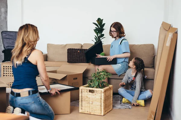 Family with cardboard boxes in new house at moving day.