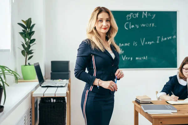 Öğretmen sınıfta kamera ayakta bakarak