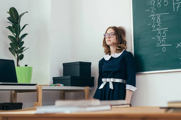 Triest schoolmeisje staande voor bord. — Stockfoto