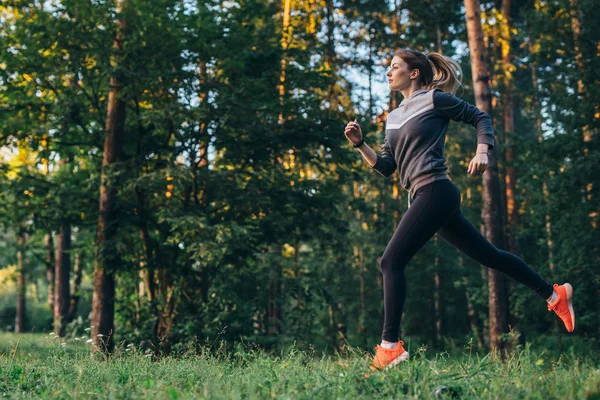 Retrato de una joven atleta con chándal corriendo en el bosque —  Fotos de Stock