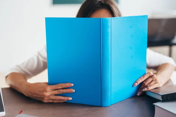 Studentka schovává za otevřená kniha — Stock fotografie