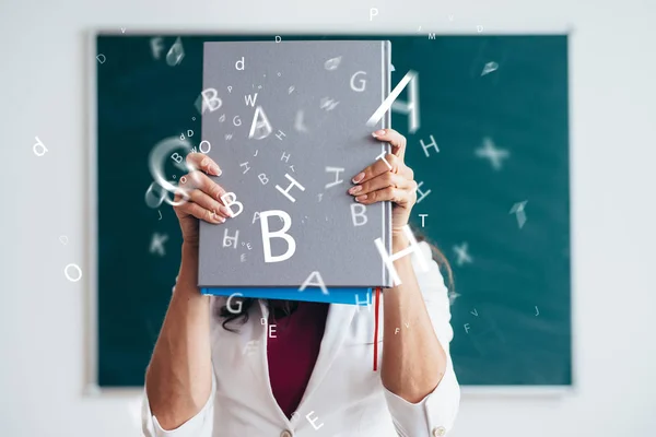 Studentka, stojící poblíž tabule s knihou — Stock fotografie