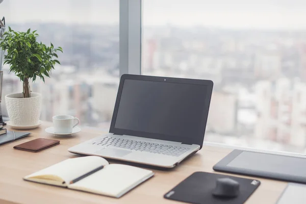 Zijaanzicht van het office-bureaublad met lege laptop en diverse hulpmiddelen. — Stockfoto