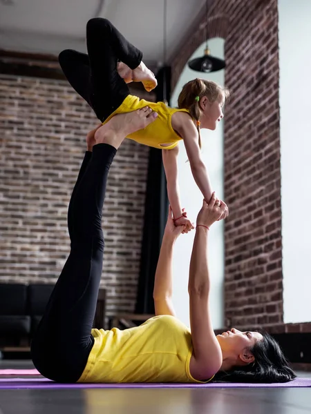 Młoda kobieta i dziewczynka robi joga partnera latający stanowią ćwiczenia razem — Zdjęcie stockowe