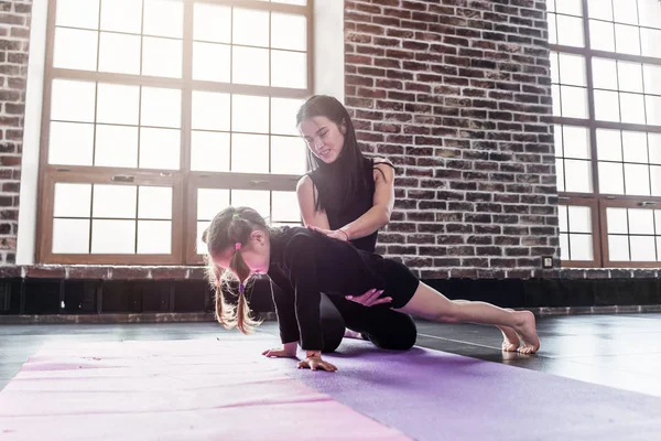 Frau zeigt kleinem Mädchen im Fitnessstudio, wie man Plankentraining macht — Stockfoto