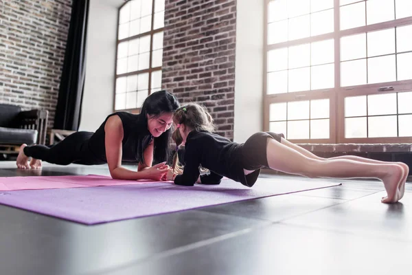 Мать и дочь работают вместе, выполняя упражнения на доске — стоковое фото