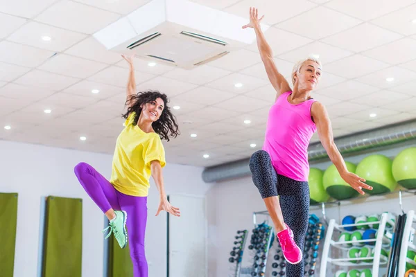 Duas jovens mulheres esportivas se exercitando no estúdio de fitness, dançando, fazendo cardio, trabalhando no equilíbrio e coordenação . — Fotografia de Stock