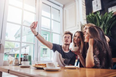 Sevimli genç selfie cep telefonu ile iç retro tarzı ile bir restoranda otururken alarak grup.