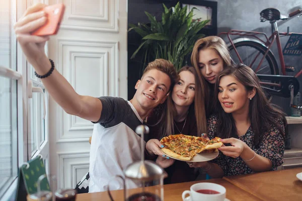 Group of cute teenagers taking selfie with cellphone while sitting in a restaurant with interior in retro style — Stock Photo, Image