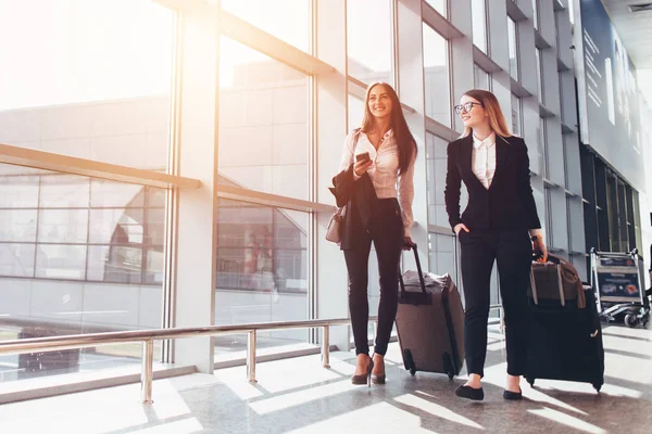 Twee glimlachend zakenpartners gaande zakelijke reis met koffers terwijl het lopen door de luchthaven doorgang — Stockfoto