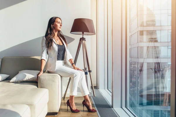 Женщина сидит на диване в современной квартире — стоковое фото