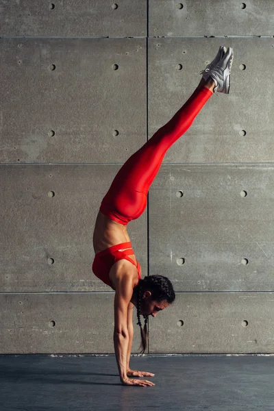 Joven mujer en forma haciendo ejercicio de pie de manos en estudio . —  Fotos de Stock