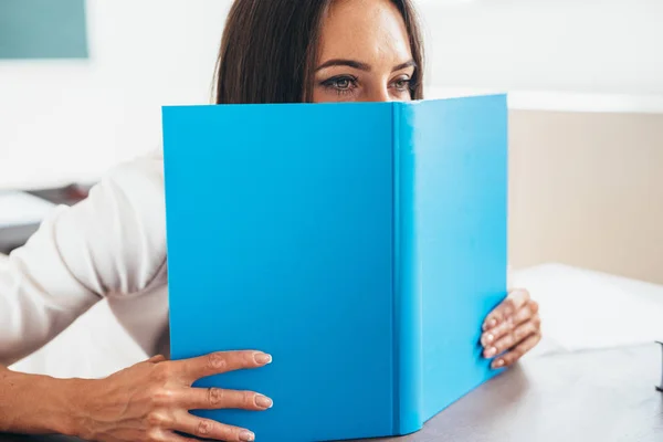 Female student hiding behind an open book — Stock Photo, Image