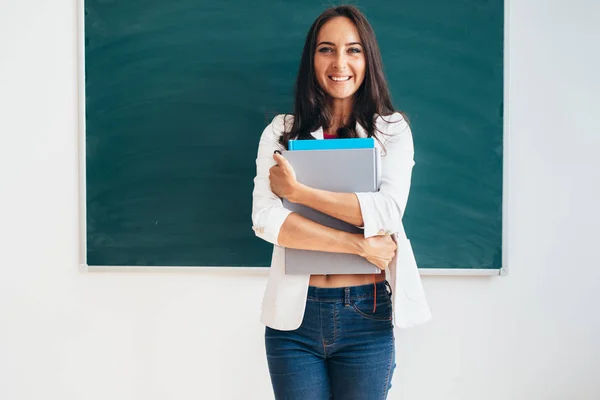 Kvinnlig student med böcker leende och tittar på kameran — Stockfoto