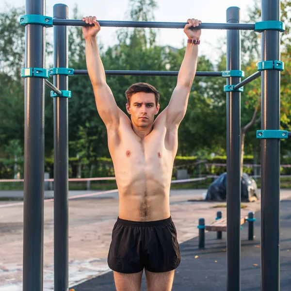 Giovane atleta di sesso maschile che fa esercizi di mento nel parco. Fitness uomo che lavora fuori — Foto Stock