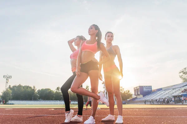 Gruppo di giovani sportivi in forma in piedi nello stadio di atletica e in posa . — Foto Stock