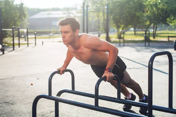 Jonge gespierde mannelijke atleet push-up beoefening in het park. — Stockfoto
