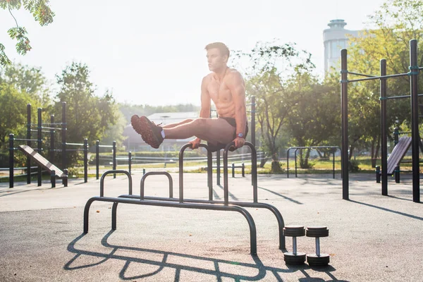 Junge starke Athletin trainiert im Outdoor-Fitnessstudio, macht Beinheben Bauchmuskeltraining. — Stockfoto