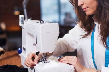 Dikiş makinesi bir atölyede çalışan genç kadın moda tasarımcısı