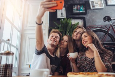 Sevimli genç selfie cep telefonu ile iç retro tarzı ile bir restoranda otururken alarak grup