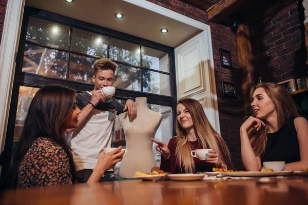 Serious young people sitting in a fashionable cafe drinking tea discussing — Stock Photo, Image