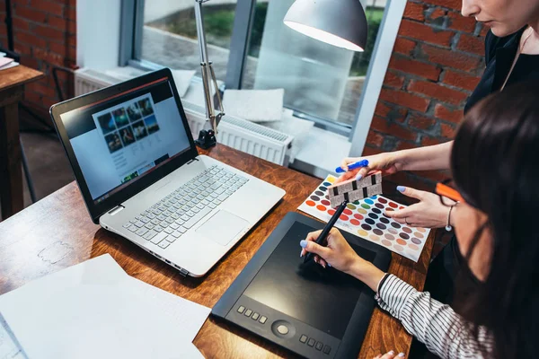 Equipo de diseñadora de interiores femenina dibujando un nuevo proyecto utilizando tableta gráfica, portátil y paleta de colores sentado en el escritorio en el estudio moderno — Foto de Stock