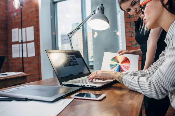 Vrouwelijke binnenhuisarchitect, werken met een klant die kijken naar foto's met behulp van laptop zit op moderne studio — Stockfoto