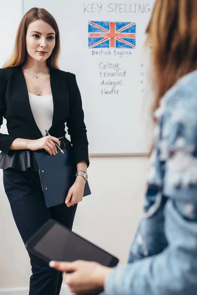 Two female students talking in classroom. College, English language school. — Stock Photo, Image