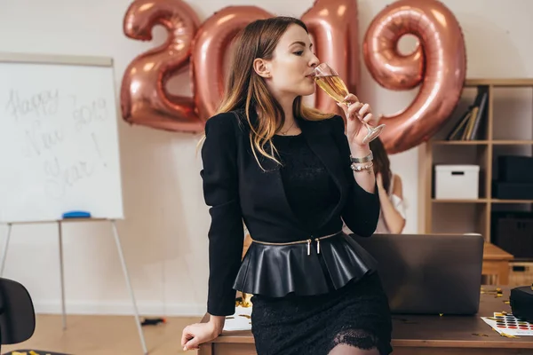Retrato de uma jovem mulher no escritório bebendo champanhe . — Fotografia de Stock