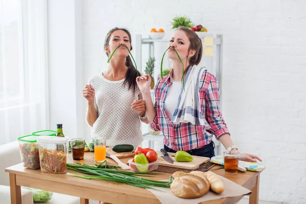 Женщины готовят здоровую пищу, играя с овощами на кухне, имея веселое понятие диеты питания — стоковое фото