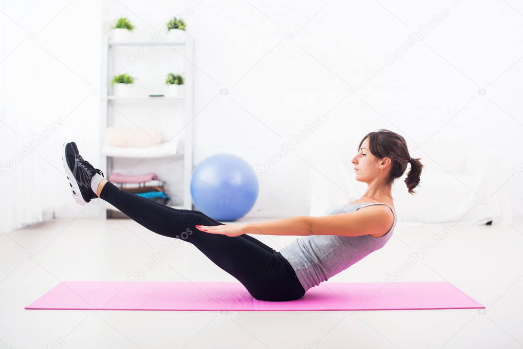 Woman doing abdominal exercise on mat at home stretching pilates yoga fitness, sport, training.