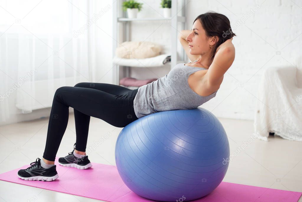 Fitness young woman doing abdominal crunches on fit ball.