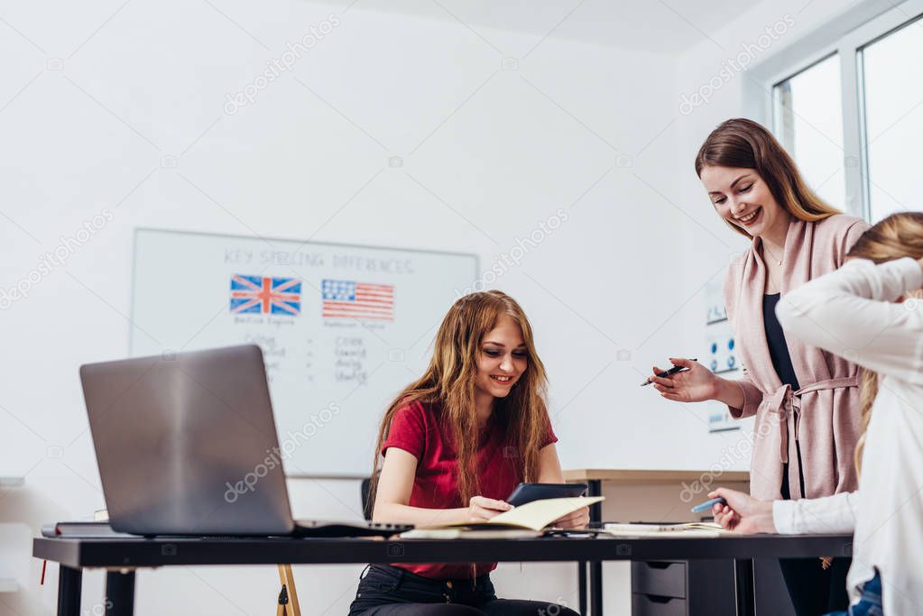 Young woman teaching English to adult students at language school.