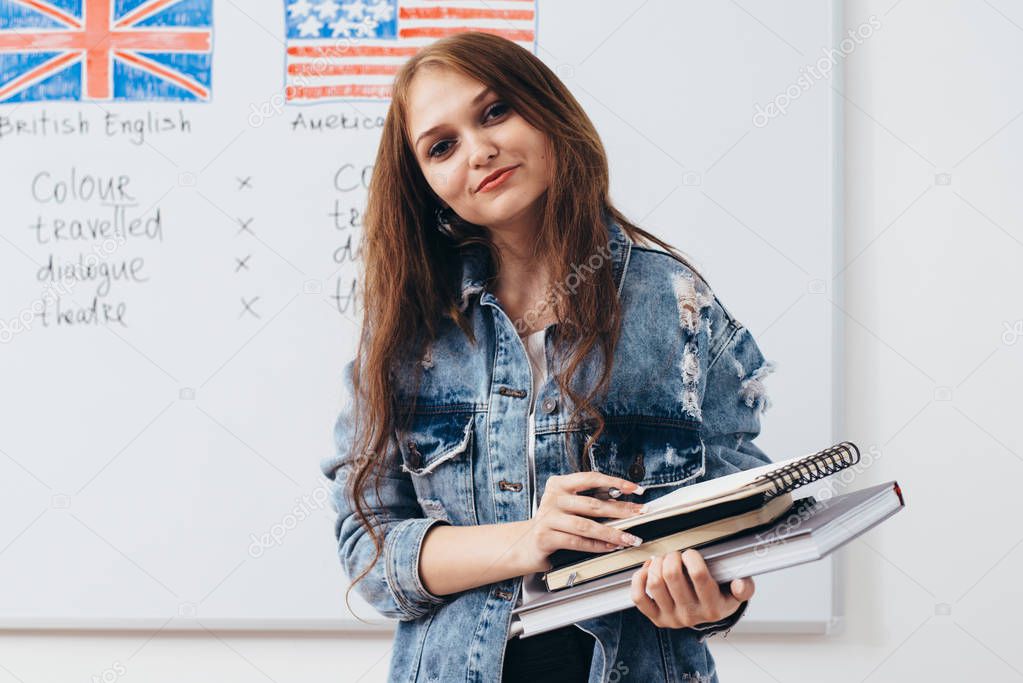 Female student with books in classroom English language school.
