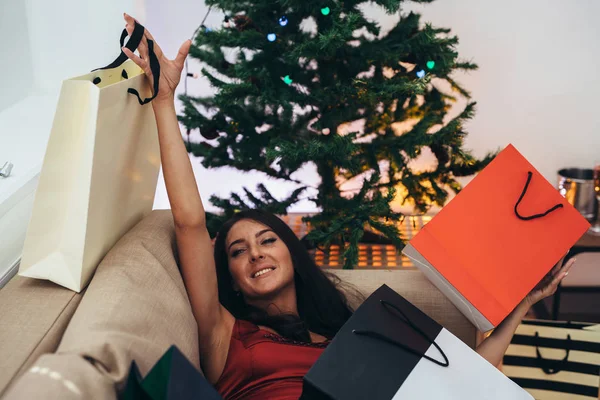 Noel ağacı tarafından siting ve alışveriş çantası dışında bir hediye alarak kadın — Stok fotoğraf
