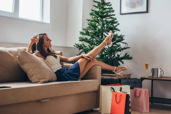 Женщина сидит у рождественской елки и вынимает подарок из сумки — стоковое фото