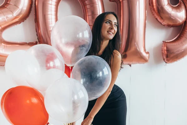 Γυναίκα που κρατά μπαλόνια που βλέπουν τα φωτογραφικών μηχανών. Νέο έτος γιορτή Ενοικιαζόμενα — Φωτογραφία Αρχείου
