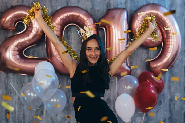 Mujer en vestido negro y corona amarilla celebrando año nuevo, divirtiéndose —  Fotos de Stock