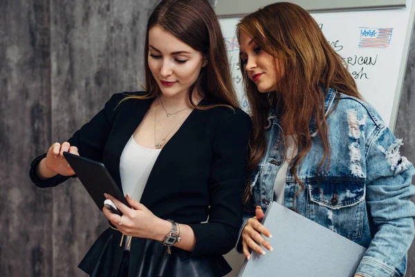 Twee jonge vrouwen kijken scherm van tablet Pc met behulp van de mobiele toepassing. — Stockfoto