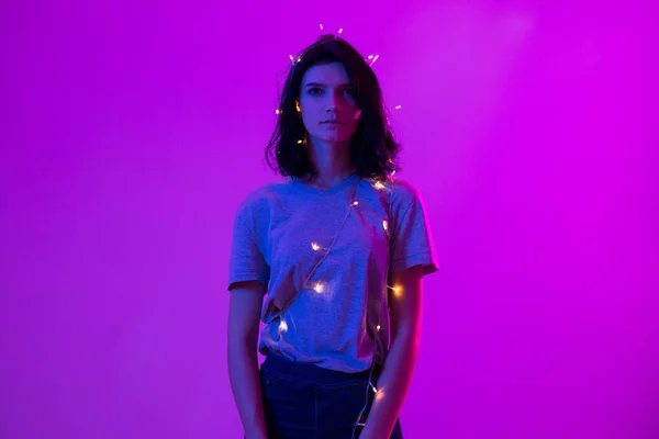 Porträtt av ung kvinna med hängande christmas lights på hennes kropp — Stockfoto