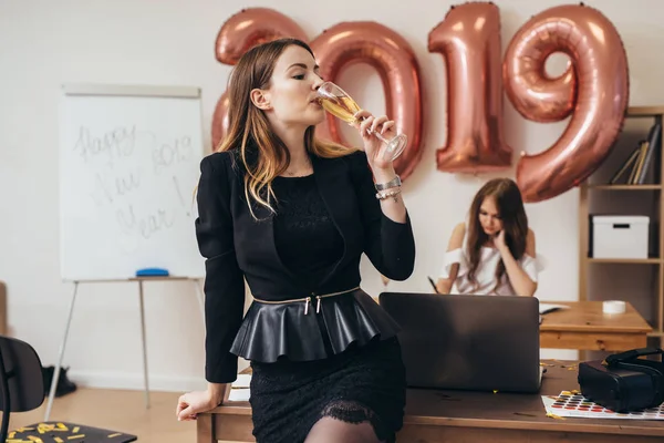 Портрет молодой женщины в офисе, пьющей шампанское — стоковое фото