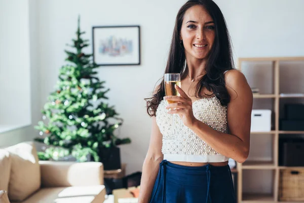 Χριστούγεννα, Πρωτοχρονιά. Χαμογελαστή γυναίκα στο σπίτι με ποτήρι αφρώδους οίνου. Διακοπές, γιορτή — Φωτογραφία Αρχείου