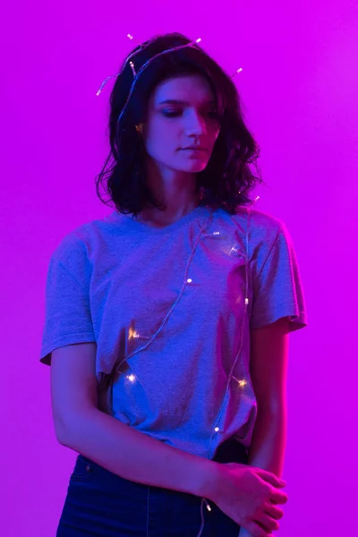 Portret van een jonge vrouw met kerst opknoping lichten op haar lichaam — Stockfoto